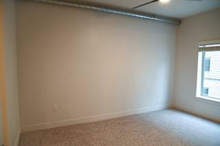 A room with a window on the right side and a carpet on the floor.