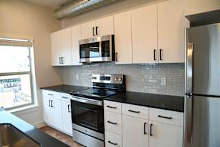 White cabinets with black countertops and subway tile backsplash at The Revival Apartments, Salt Lake City