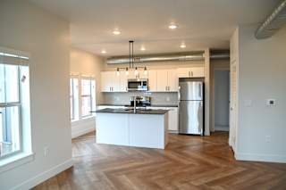 Open kitchen with white island and exposed ductwork at The Revival Apartments, Utah, 84101