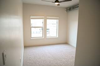 Carpeted bedroom with two windows and ceiling fan at The Revival Apartments, Salt Lake City, Utah