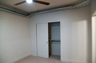 Carpeted bedroom with open closet and exposed ceiling duct at The Revival Apartments, Salt Lake City