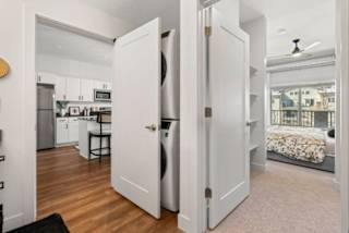 A small kitchen with a refrigerator, a washing machine, and a dining table.
