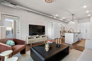 A living room with a red armchair, a black coffee table, and a television.