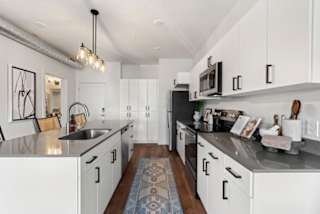 A kitchen with white cabinets and a black countertop.