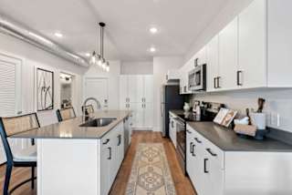 A modern kitchen with white cabinets and a black countertop.