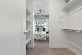 A white room with a bed and a ceiling fan.