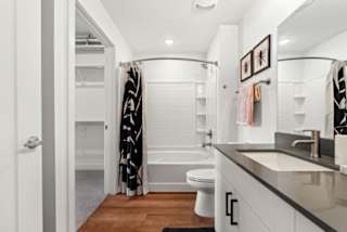 A bathroom with a white toilet, a sink, and a shower with a black and white curtain.