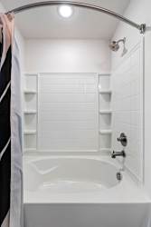 A white bathtub with a shower head and a towel hanging on the side.