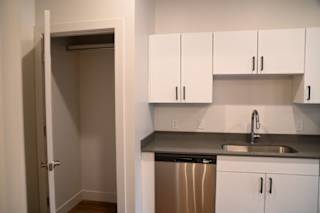 Kitchenette with stainless steel dishwasher and gray countertops at The Revival Apartments, Salt Lake City, 84101