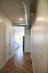 A long hallway with wood floors and white walls.