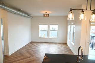A kitchen with a black countertop and wooden flooring.