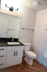 A white toilet sits in a bathroom next to a sink and a mirror.