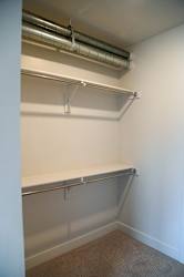 A white wall with a metal pipe and a shelf.
