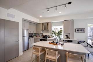 A modern kitchen with a white island and wooden chairs. at Paperbox Lofts Apartments, Salt Lake City  , Utah