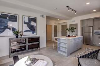A modern kitchen with a refrigerator, microwave, and a dining table with chairs. at Paperbox Lofts Apartments, Utah