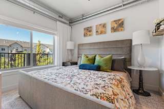 A bedroom with a large bed and a view of houses through the window. at The Revival, Salt Lake City, UT 84101