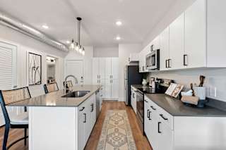 A modern kitchen with white cabinets and a black countertop.