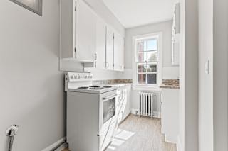 A kitchen with white cabinets and a stove top oven.
