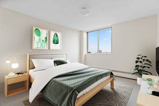 A bedroom with a large bed and a green blanket.