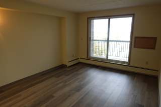 A room with wooden floors and a window overlooking a balcony.