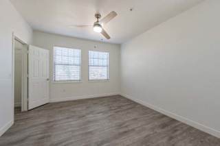 A room with a ceiling fan and two windows.