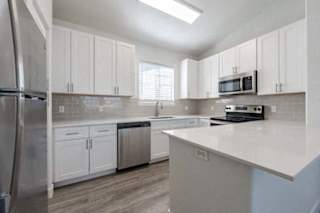 A kitchen with white cabinets and a stainless steel refrigerator.