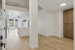 an open kitchen and living room with white walls and wood floors