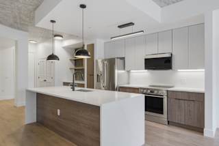 a white kitchen with a large island and stainless steel appliances