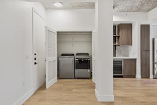 a renovated living room with a refrigerator and a washer and dryer in it
