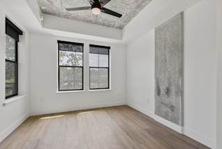 an empty room with white walls and wood floors and a ceiling fan