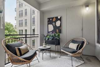 an apartment balcony with two chairs and a table and a potted plant