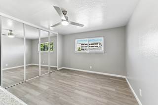A room with a ceiling fan and a window showing a building outside.