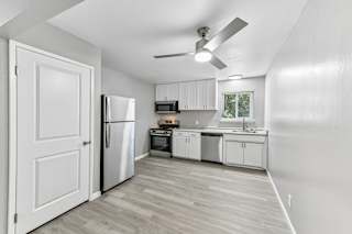 A kitchen with white cabinets and a refrigerator.