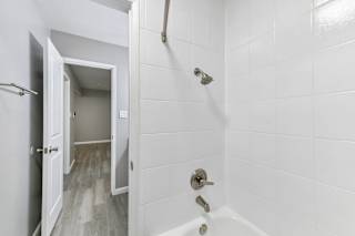 Bathroom with tub/shower with white tile walls, curved shower curtain rod, and towel bar.