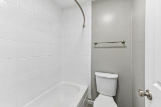 A white toilet sits next to a white bathtub in a bathroom.