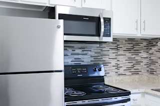 A modern kitchen with a stainless steel refrigerator, microwave, and stove.