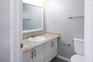 A bathroom with a sink, toilet and mirror.