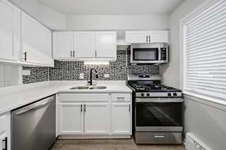 A kitchen with white cabinets and a black and white tiled backsplash.