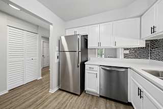 A modern kitchen with white cabinets and a stainless steel refrigerator.