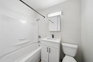 A white bathroom with a tub, sink, and toilet.