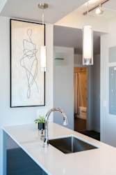 A modern kitchen with a white countertop and a large abstract painting above it.
