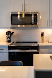 A modern kitchen with a black stove and white cabinets.