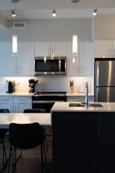 A modern kitchen with a stainless steel refrigerator and black chairs.