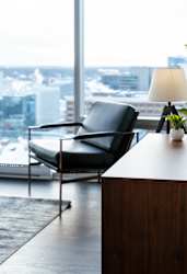 A black chair is placed in front of a window with a view of a cityscape.