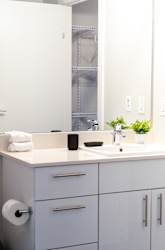 A white bathroom with a sink, mirror, and cabinets.