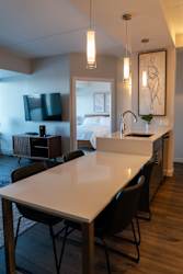 A modern kitchen with a long white table and black chairs.