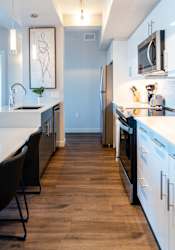 A kitchen with black chairs and a white counter.