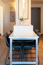 A white dining table with four chairs and a plant on top.