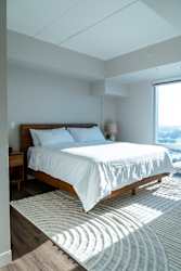 A bedroom with a large bed and a window overlooking the city.