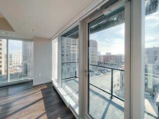 a bedroom with a large window and hardwood floors